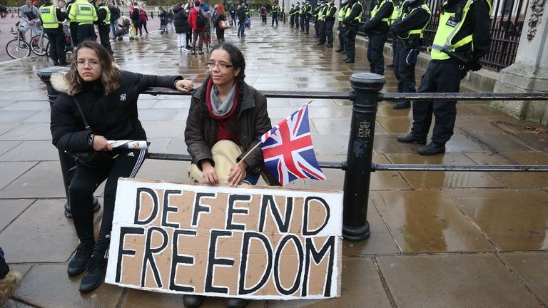 Demonstrators sit in front of a police cordon outside Buckingham Palace