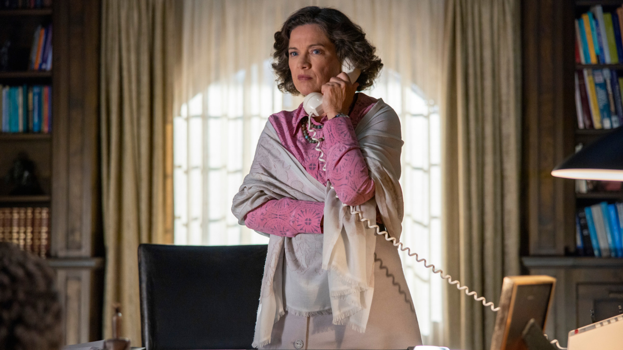 Woman wearing a pink shirt answers the phone.