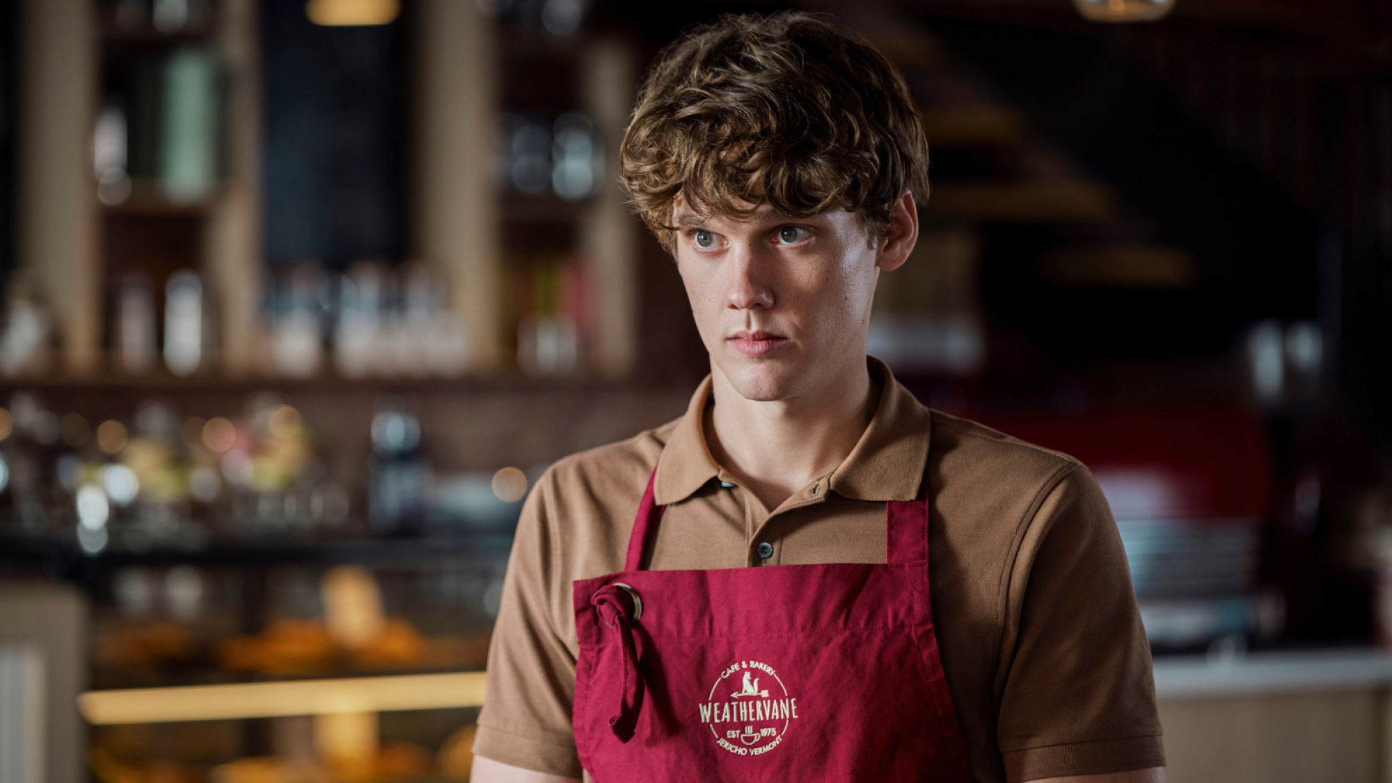 A teen in a polo shirt and barista apron looks menacing.