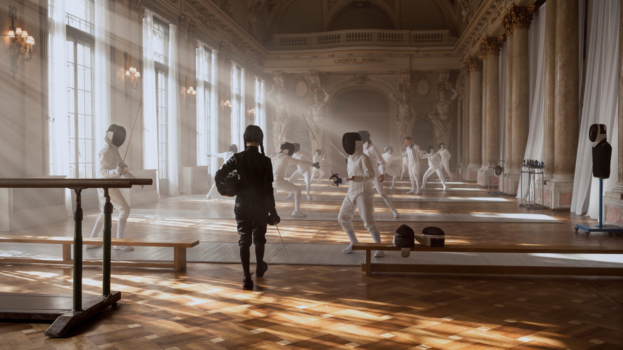 Teens in an opulent hall partake in fencing.