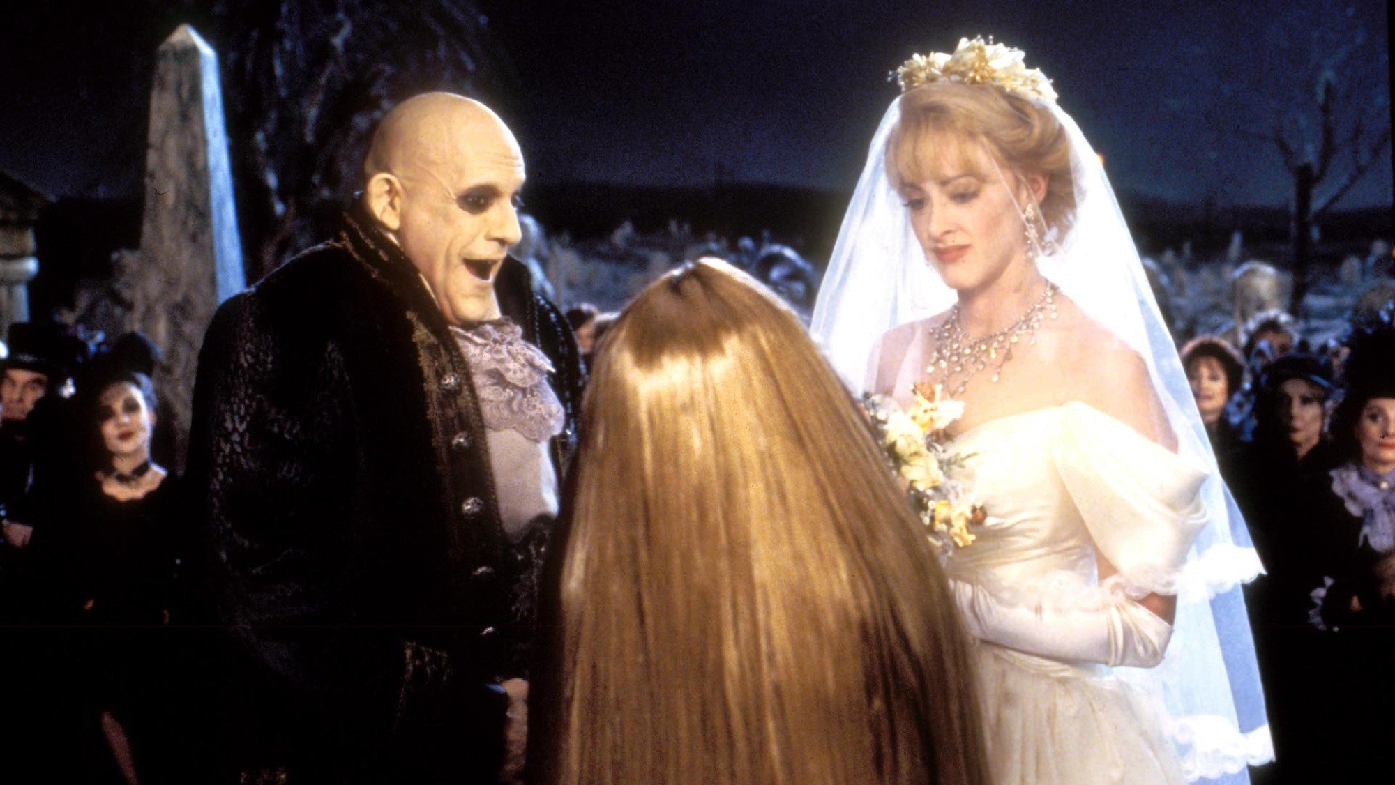 A wedding scene from the movie "Addams Family Values" with the characters Uncle Fester, Debbie, and Cousin Itt.