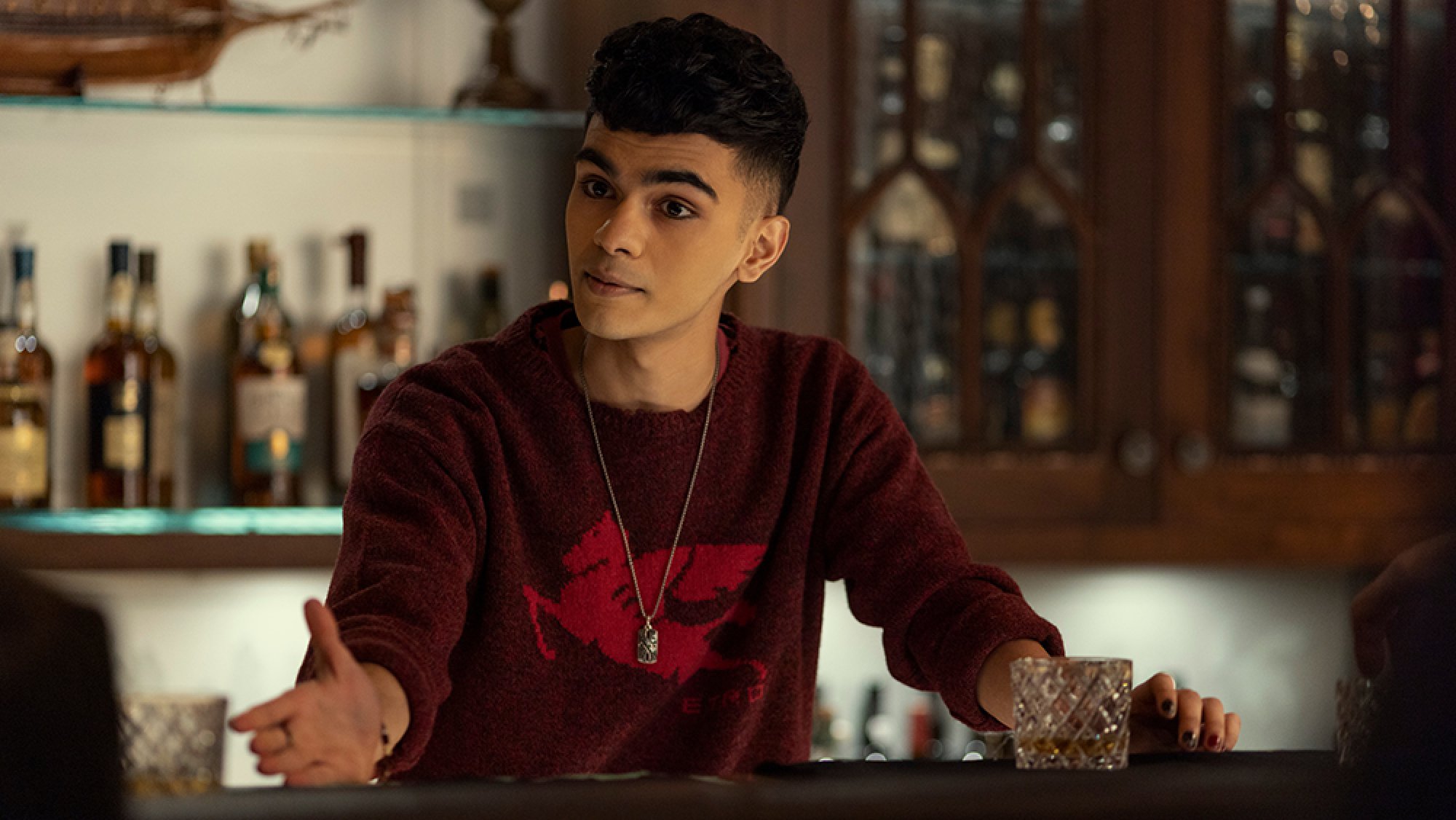 A young man stands behind a bar.