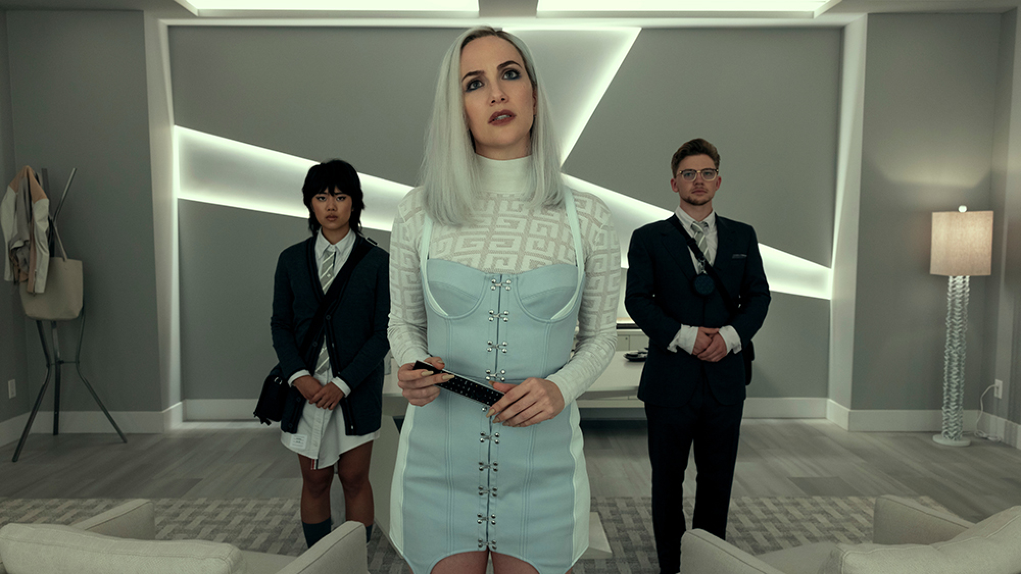A woman stands in front of a man and a woman wearing suits.