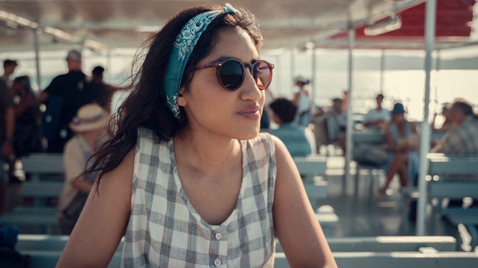 A young woman on vacation stands on a ferry.