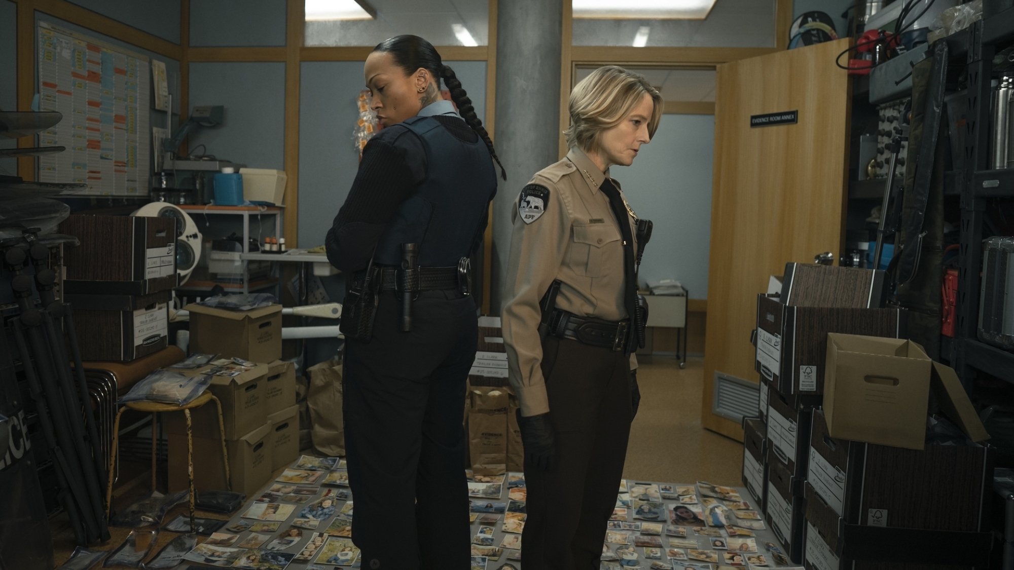Two detectives stand in a bunch of evidence.